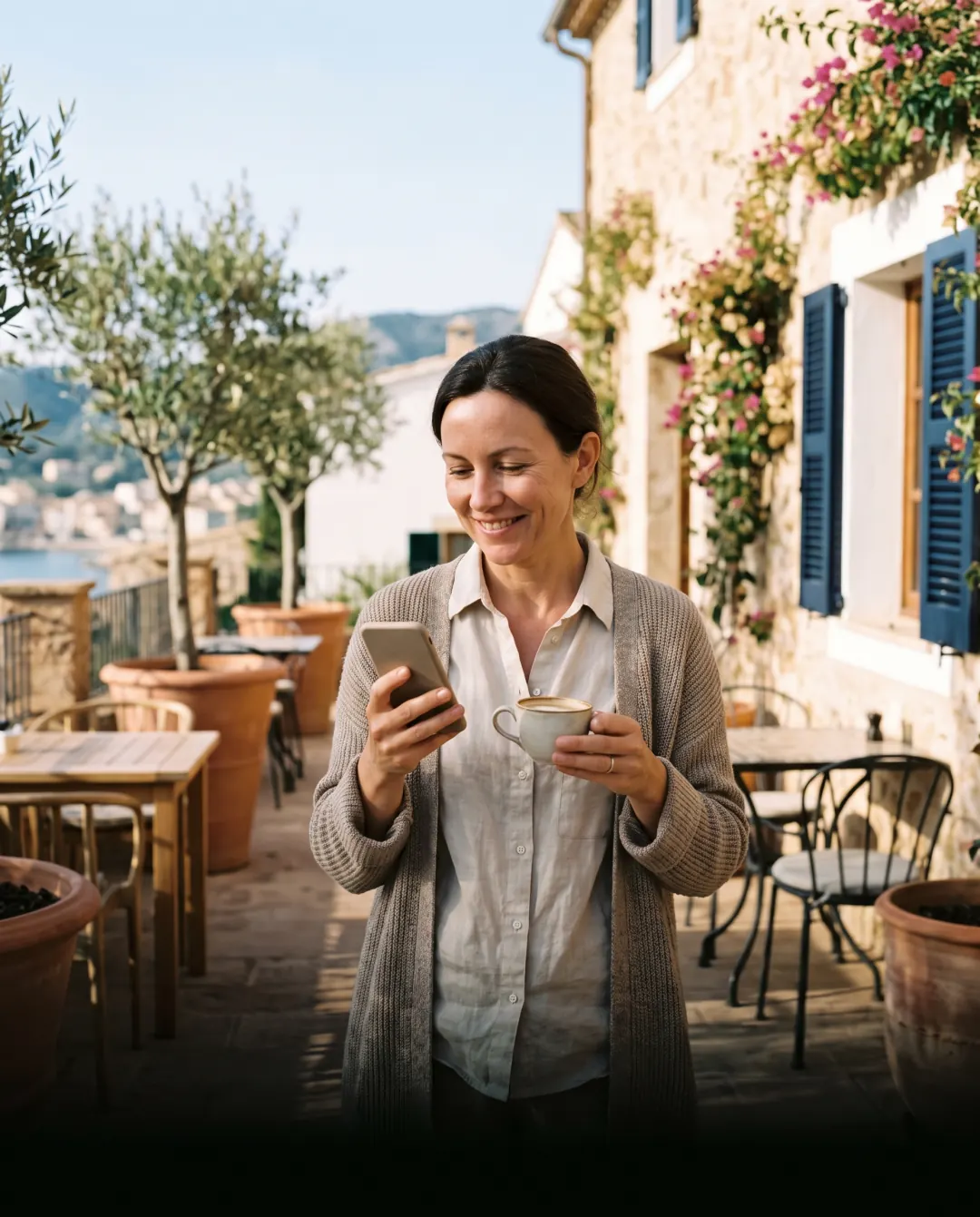 Hotel owner checking her phone with a morning coffee on the hotel terrace